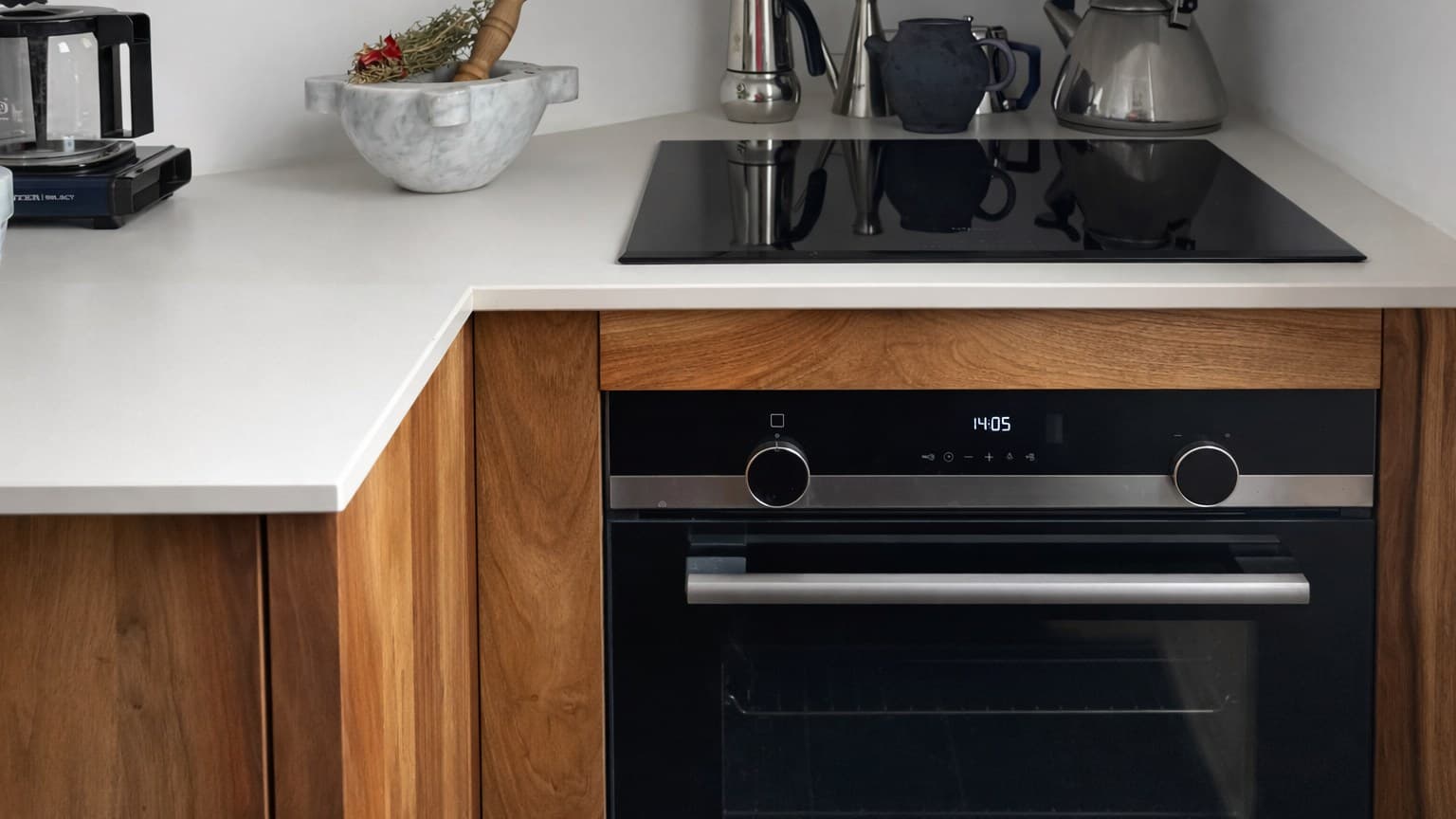 Cuisine moderne avec four noir intégré, plaque à induction et surface en quartz blanc